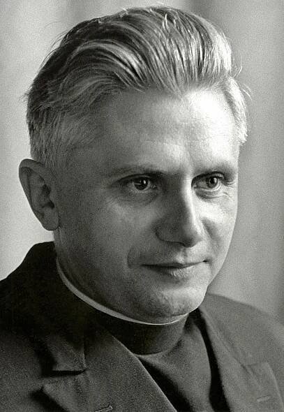 A portrait, in black and white, of a man wearing a priest's collar and a black suit.