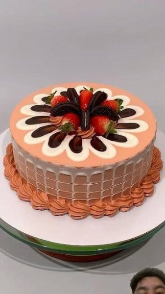 a man standing in front of a cake with strawberries on top and chocolate decorations