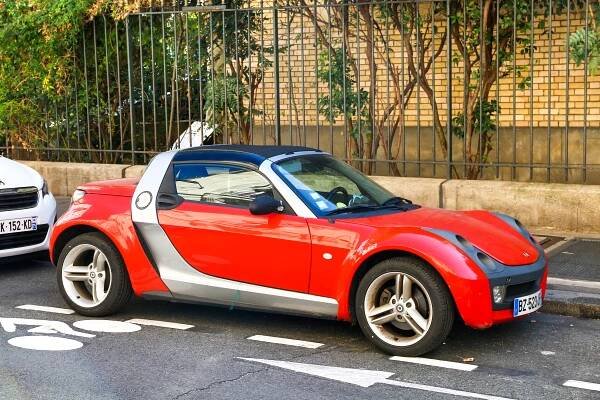 Red Smart Roadster parked on a city street.