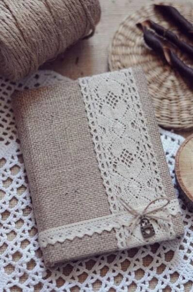 an old book is sitting on a doily next to twine and wood slices