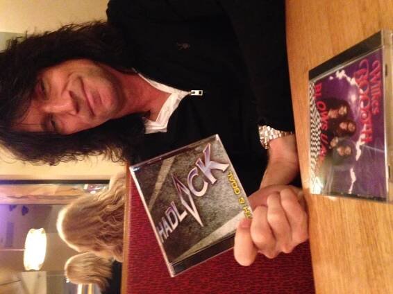 KISS's lead guitarist Tommy Thayer at a diner booth and holding a CD of an album by Hadlock