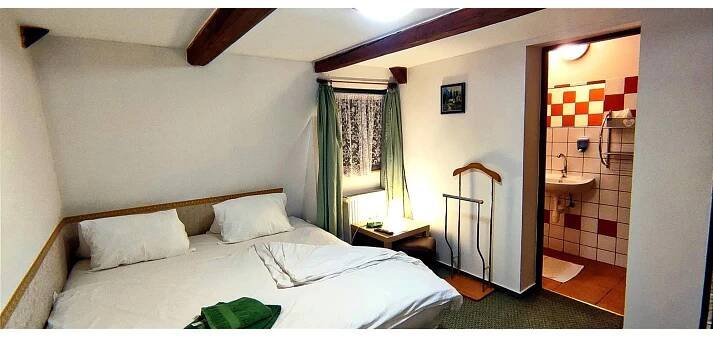 a bedroom with a bed and a bathroom with a sink at Pension Helene s mini pivovarem in Kytlice