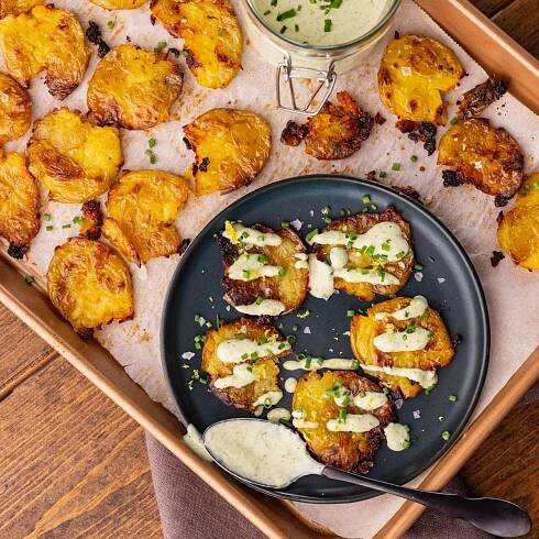 duck fat smashed potatoes with lemon chive dressing on pan of smashed potatoes.