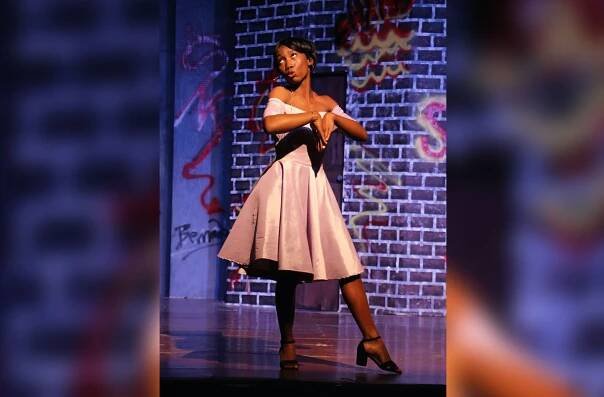A woman in a white dress is dancing on a stage