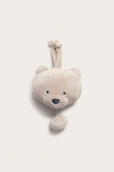 Front view of a beige plush teddy bear head music box with embroidered features and a pull-string.