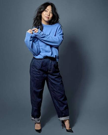 Stephanie Hsu in a blue sweatshirt, jeans, and heels