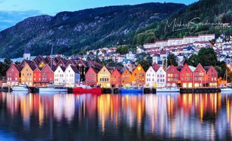 Ein Blick auf den Hafen in Norwegen mit schönen bunten Häusern und Bergen im Hintergrund.