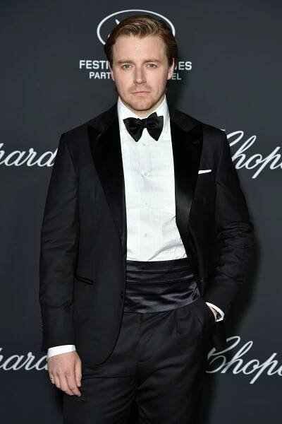 a man in a tuxedo stands in front of a sign that says chopard