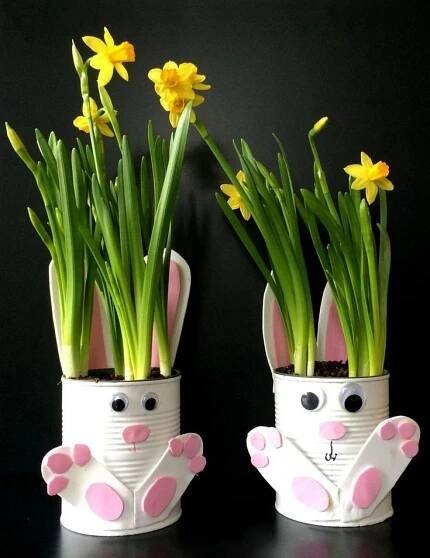 two white vases with yellow flowers in them and bunny ears on the top one