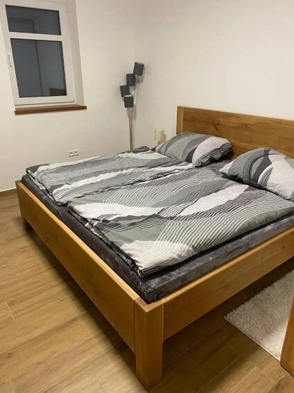 a bed with a wooden frame in a room at Vila Kosmonautka - Velké Losiny in Velké Losiny