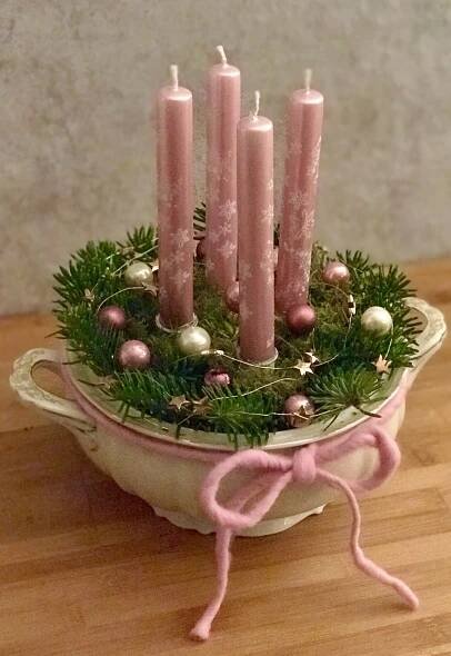 some pink candles are sitting in a bowl with ornaments on the rim and around them