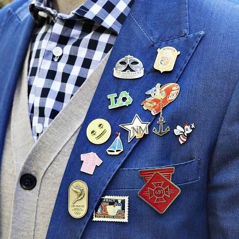 Custom made lapel pins arrayed on the lapel of a blue mens jacket