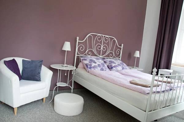 a bedroom with a bed and a white chair at Penzion Zámek Rozsochatec in Rozsochatec