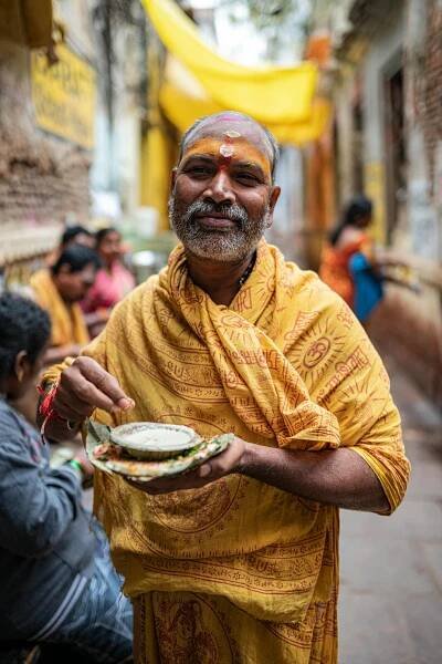 bezplatná Jihoasijský svatý muž v tradičním oděvu drží obětinu v pulzující ulici ve Varanasi. Základová fotografie