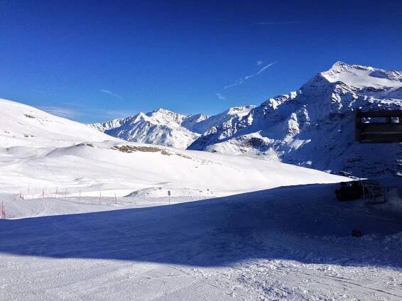 a snow covered ski slope with mountains in the background