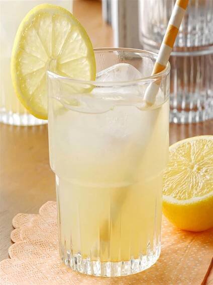 a glass filled with lemonade sitting on top of a wooden table