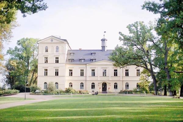 Luxurious Chateau Mcely surrounded by lush greenery and a serene lake, perfect for a peaceful getaway.