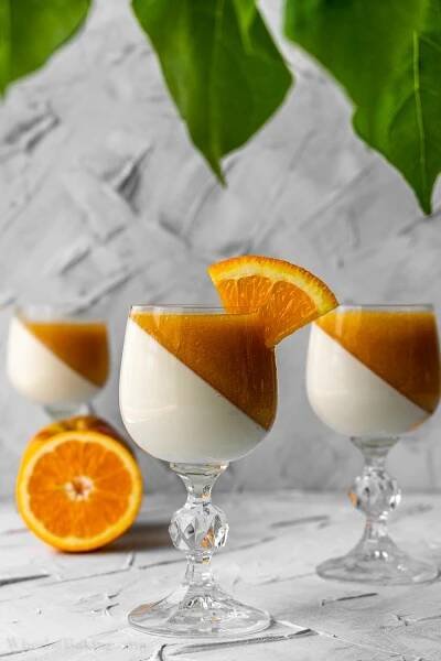 panna cotta tilted in wine glass with peach and orange juice sauce.