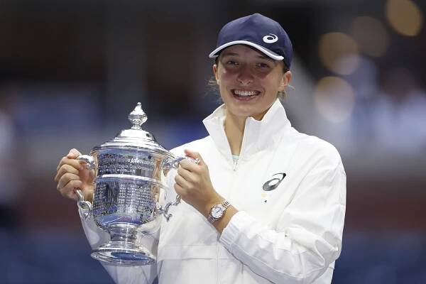Iga Swiatek poses with the US Open championship trophy. 