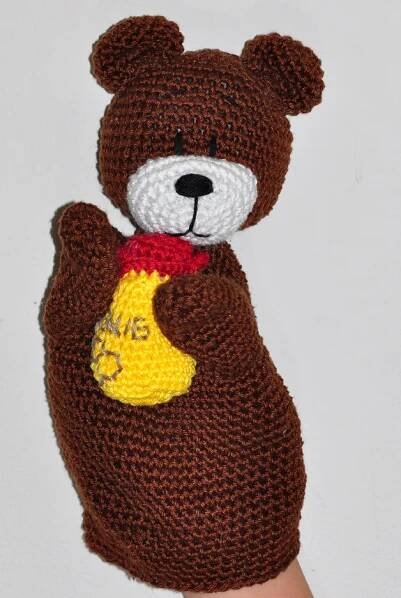 a crocheted teddy bear with a banana on it's chest is held up