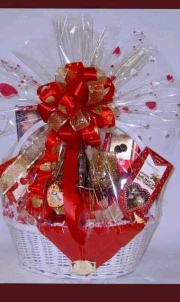 a basket filled with lots of chocolates and candies in red ribbon tied around it