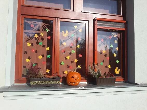 a pumpkin sitting on the window sill in front of a house with autumn decorations