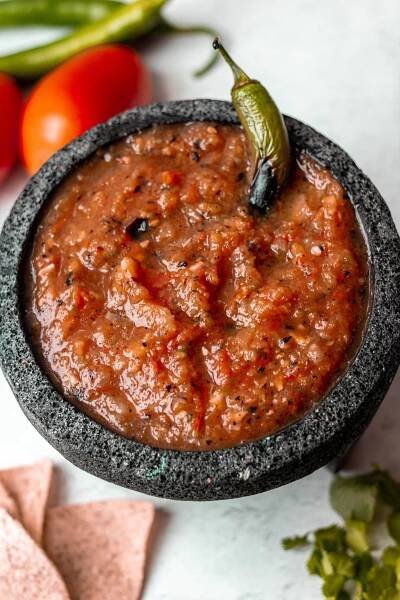 Salsa Roja in stone molcajete. Serrano pepper garnish, tomato prop