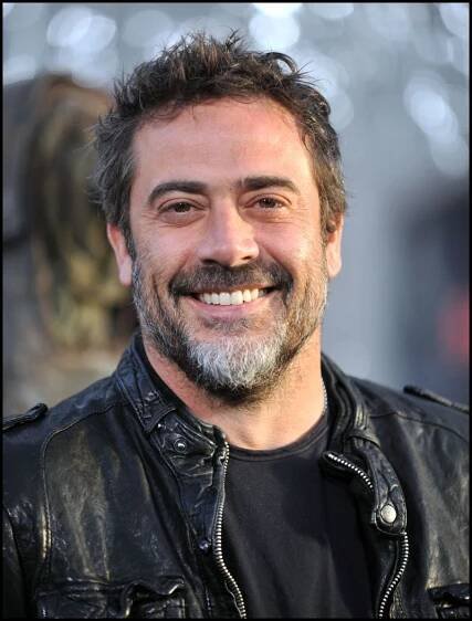 a man with a goatee smiles at the camera while wearing a black leather jacket