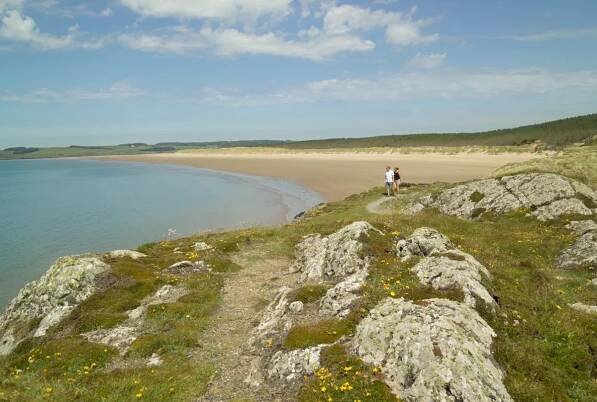 Couple walking on coastal path, Llanddwyn Island, Anglesey, North Wales