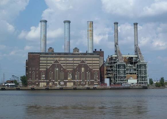 Two large buildings side by side with five massive smokestacks