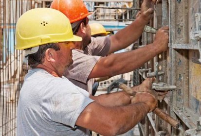 Autentické stavební dělníci umístění cementu bednění rámy na místě — Stock obrázek