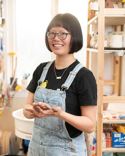 Bear with hands covered in clay smiling in her studio.