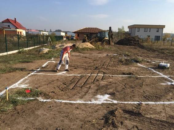 Vytyčování základů domu. Pracovník vytyčuje přesné obrysy budoucí stavby