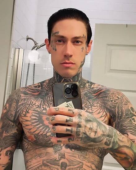Trace Cyrus without a shirt and showing off his tattoos in a mirror selfie.