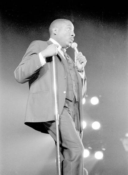 Dick Gregory speaking into a handheld microphone