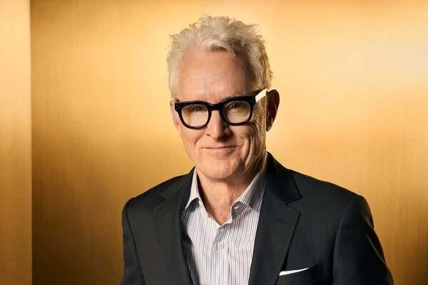 John Slattery smiling against a gold background