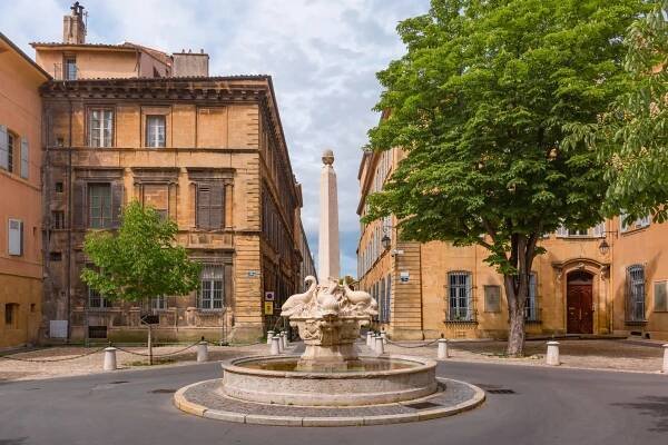 A stone fountain in the center of a circular street intersection in a historic city area