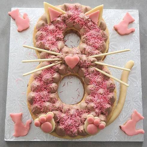 a cake decorated to look like a cat with pink icing and sprinkles