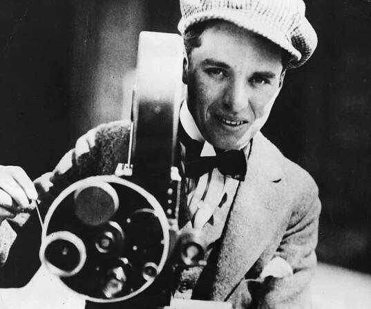 Charlie Chaplin filming wearing a suit and a hat 