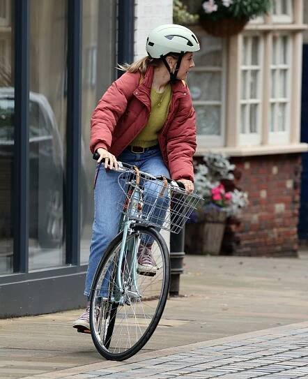 a woman wearing a helmet is riding a bike
