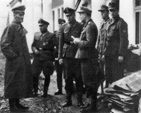 This grainy photograph is one of the few surviving images of Dirlewanger, seen here on the left in a long trench coat, with his staff