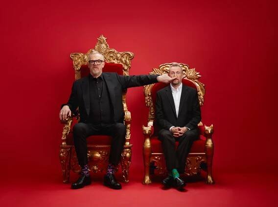 Greg Davies and Alex Horne seated in ornate gold chairs against a red background.