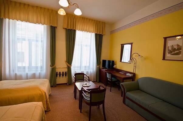 a hotel room with a bed and a couch and a desk at Grandhotel Garni in Jihlava