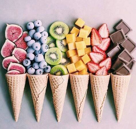 four ice cream cones filled with different types of fruit