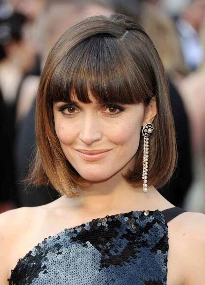 Rose Byrne in a short bob haircut with bangs, a deep side part, and flipped-in ends
