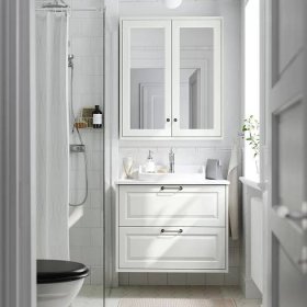 Bílá koupelna s umyvadlovou skříňkou TÄNNFORSEN se zásuvkami a polozapuštěným umyvadlem RUTSJÖN pod zrcadlovou skříňkou.