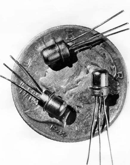 Picture dated 1956 of three miniature M-1 transistors seen on the face of a dime