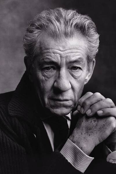 black and white photograph of an older man with his hands on his chin, looking at the camera