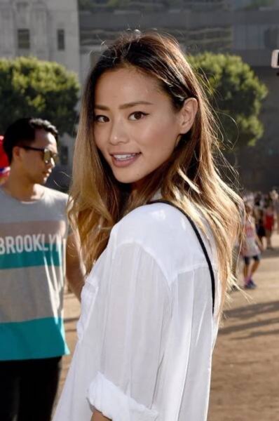 a beautiful young woman standing in front of a group of people on a sunny day