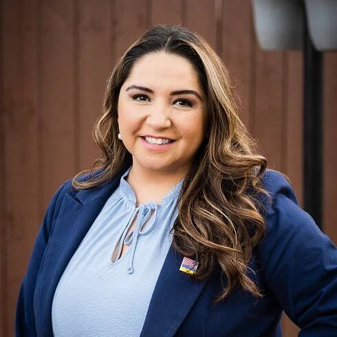 A woman wearing a blue jacket and a blue shirt is smiling for the camera.
